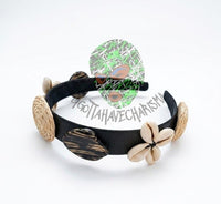 This black headband features natural decorative elements like wood pieces and shells for a beach-inspired look